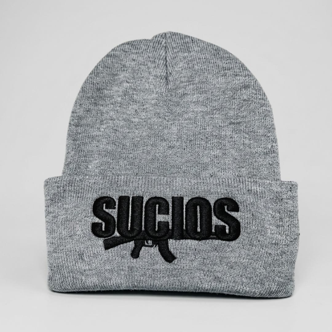 A heather gray ribbed knit beanie hat with a folded cuff, featuring a black embroidered logo that reads 'SUCILOS' with a rifle graphic underneath, set against a plain light gray background.